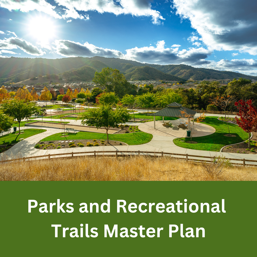 A landscaped park with walking paths, seating areas, and a pavilion set against rolling hills